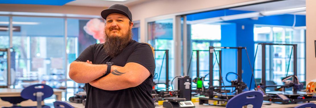 Marc Vaughn stands arms crossed with a grin in the Makerspace at East Campus
